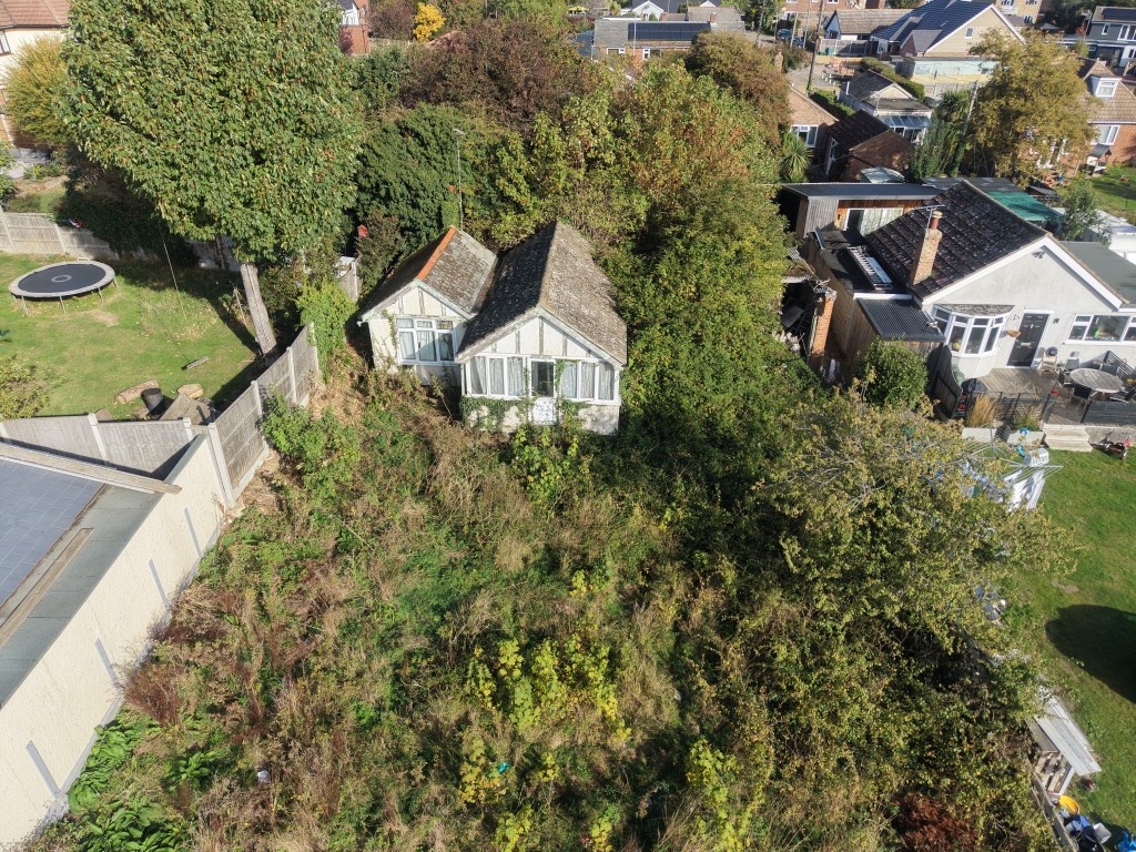 Lot: 55 - ONE-BEDROOM DETACHED COTTAGE FOR DEMOLITION ON APPROXIMATELY 0.14 ACRES OF LAND - Aerial view showing further overgrown land to the rear